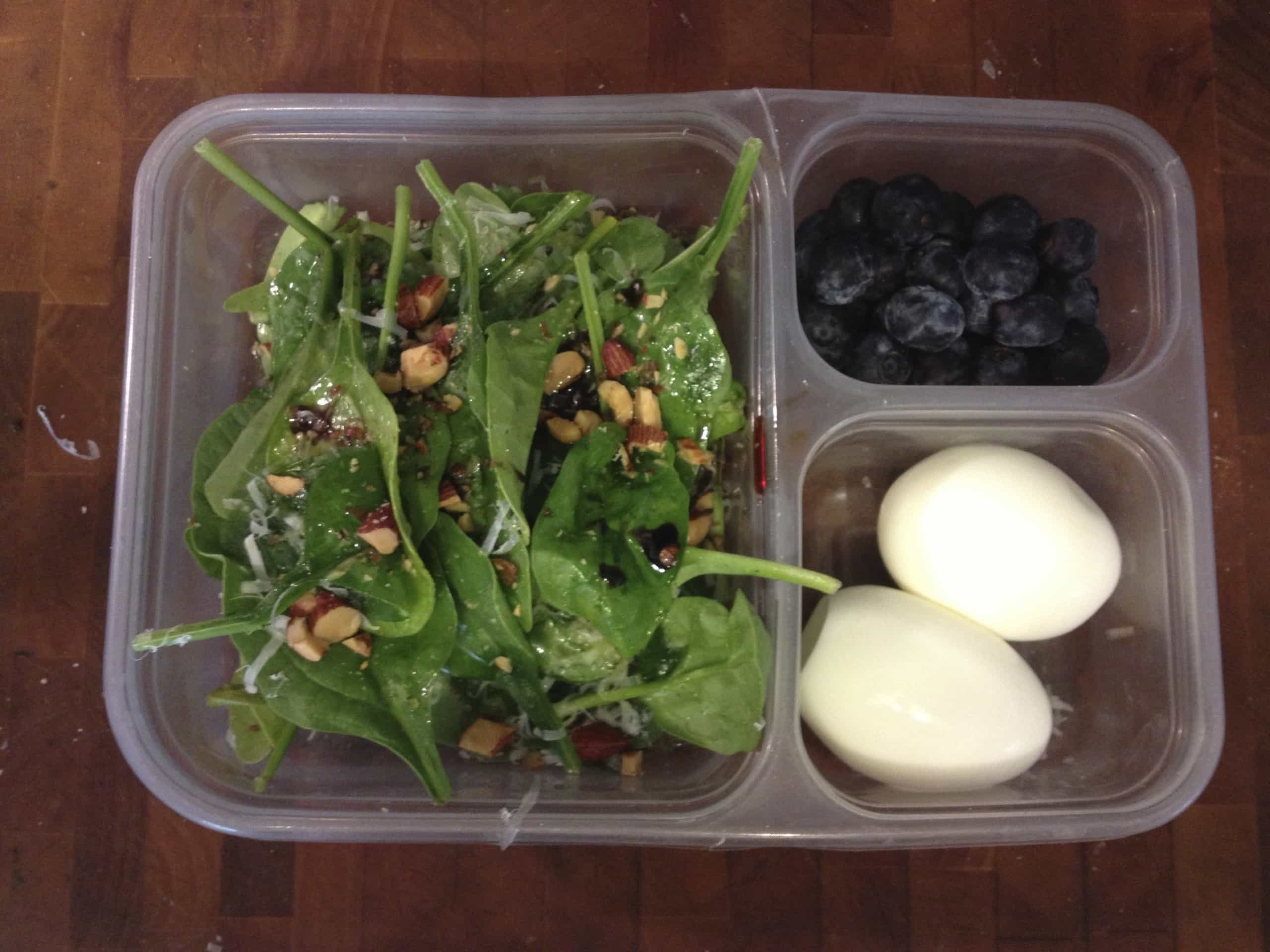 Brown bag lunch of salad, eggs, and blueberries