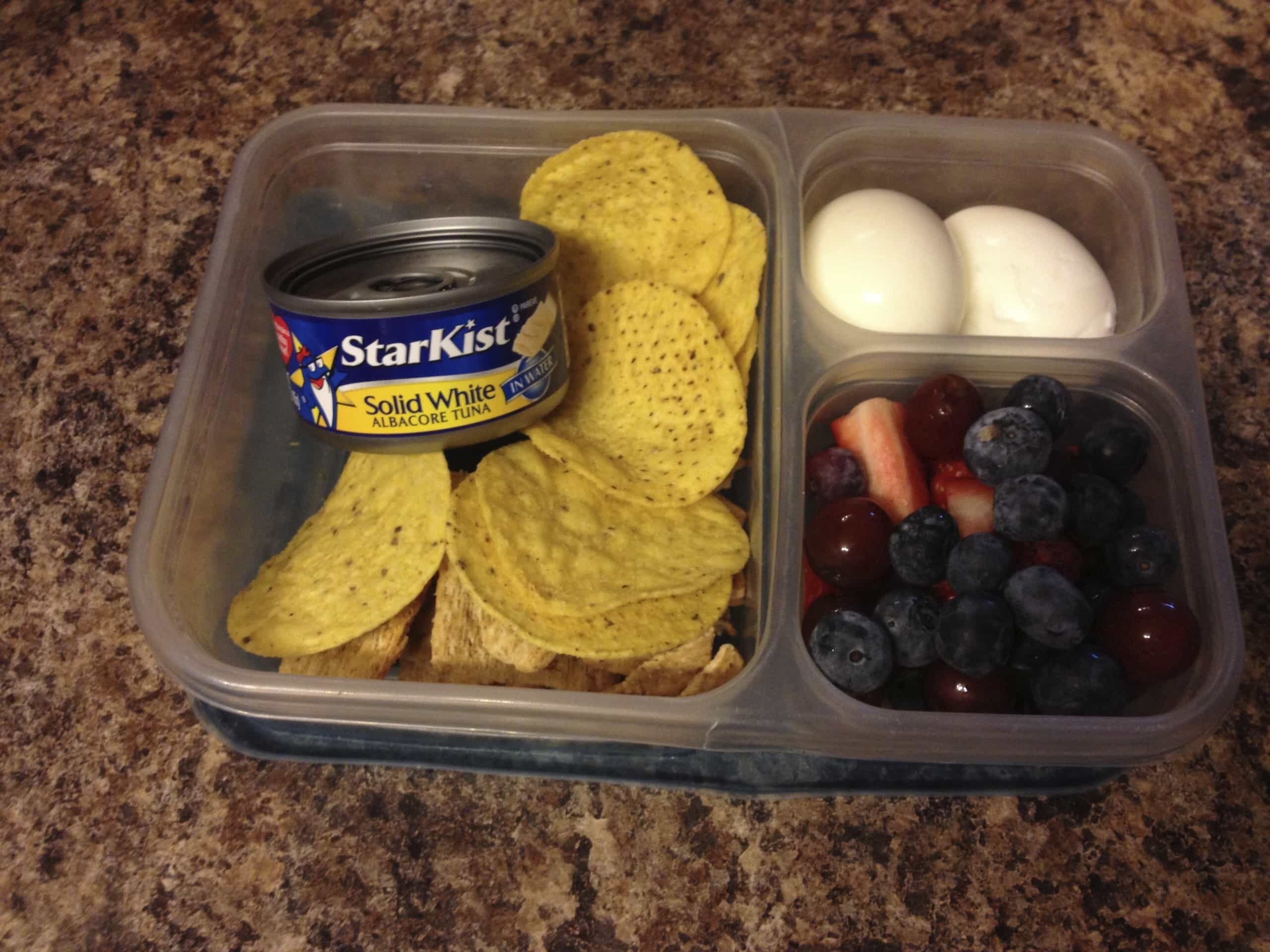 Packed lunch of tuna, fruit, and hard boiled eggs.