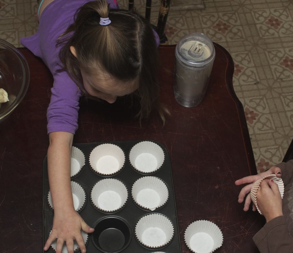 kids helping line a muffin tin