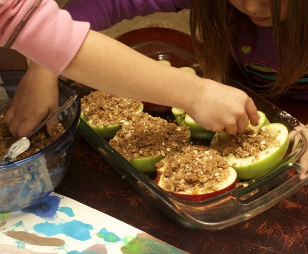 Kids sprinkling toppings on baked apples