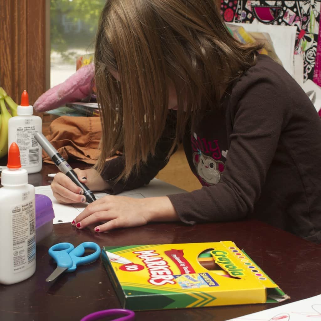 Young girl coloring with gray marker. 