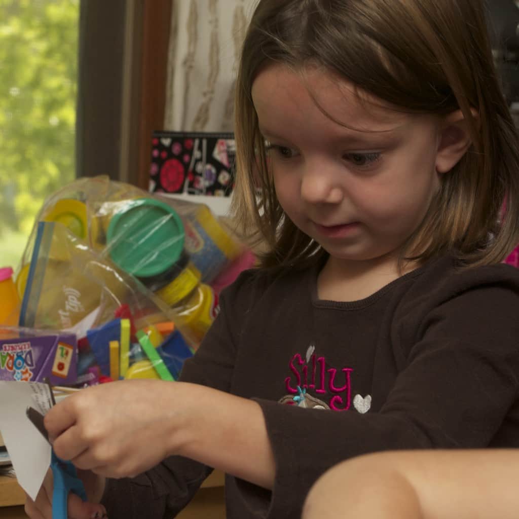 5 year old cutting paper with a scissors.