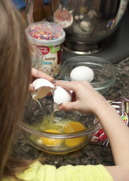 6 year old girl cracking eggs for baking. 