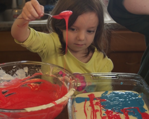 Little girl adding batter to the cake pan. 