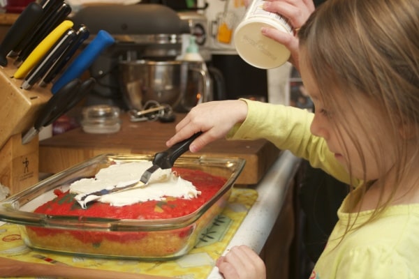 6 year old girl frosting a cake. 