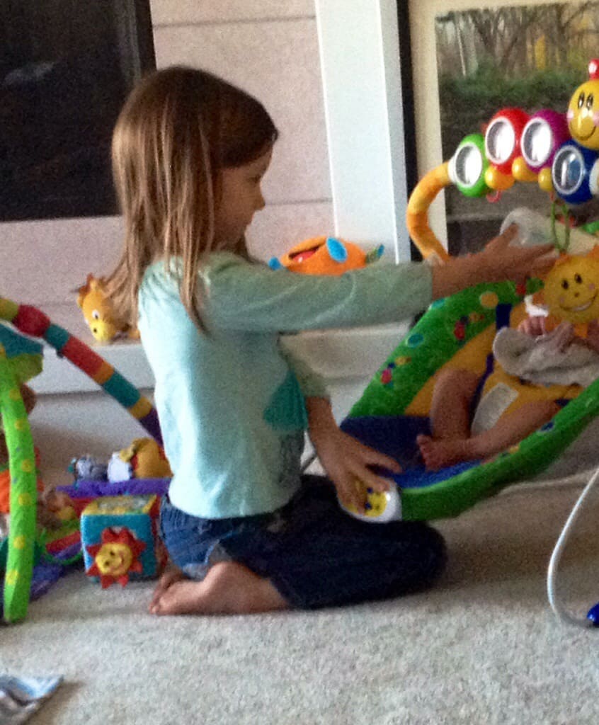 Girl bottle feeding her baby cousin