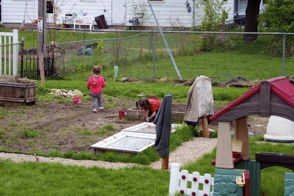 Young sisters play digging in the family garden.