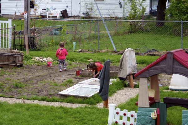 Young sisters play digging in the family garden. 