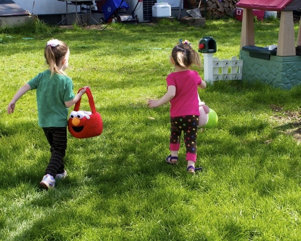 Young sisters having an Easter egg hunt in their backyard.