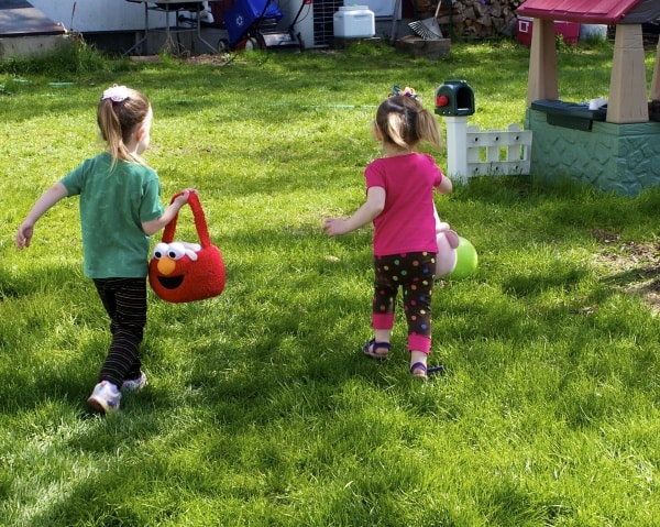 Young sisters having an Easter egg hunt in their backyard. 