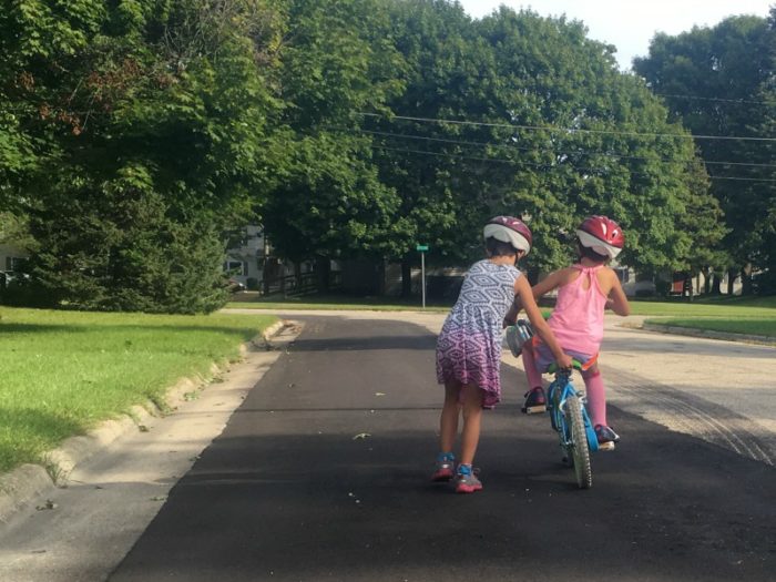 older sister helping sibling ride her bike