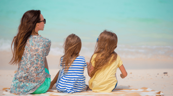 Mom and 2 daughters sitting at the beach