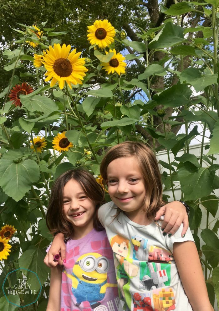 Sisters in front of sunflowers in their backyard