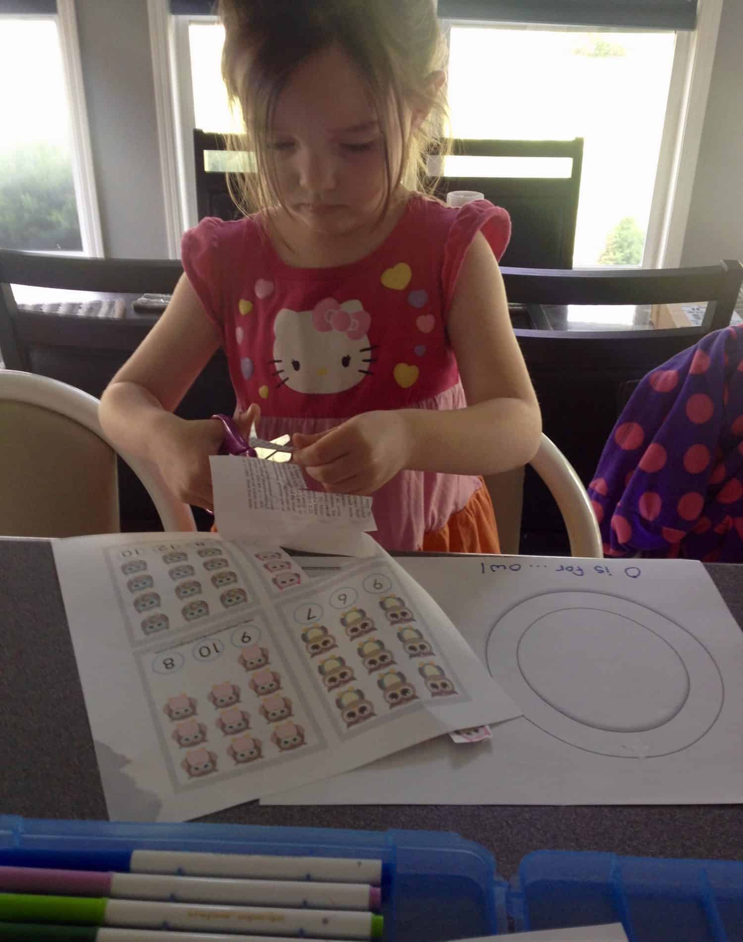 Preschooler gluing paper owls onto a big letter O