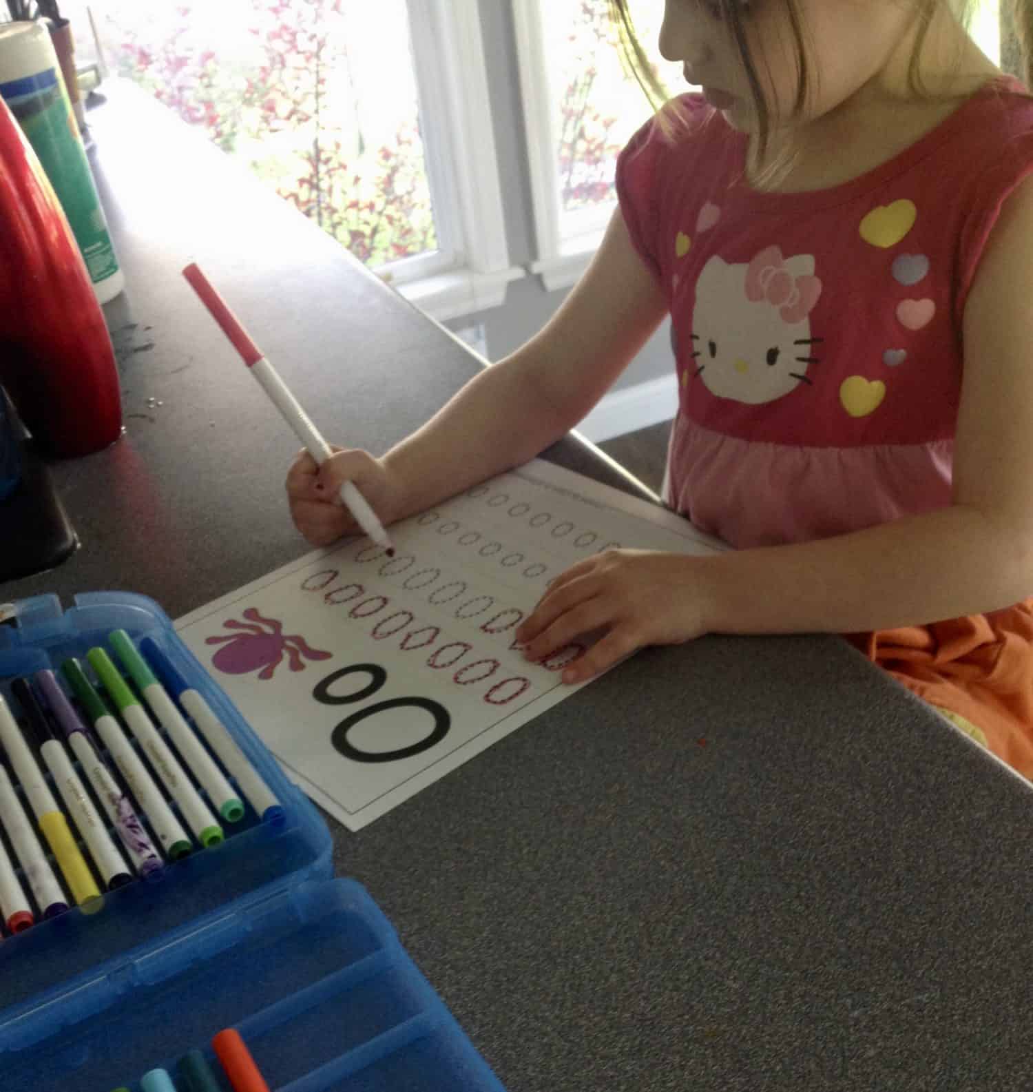 Preschooler tracing the letter o on a worksheet