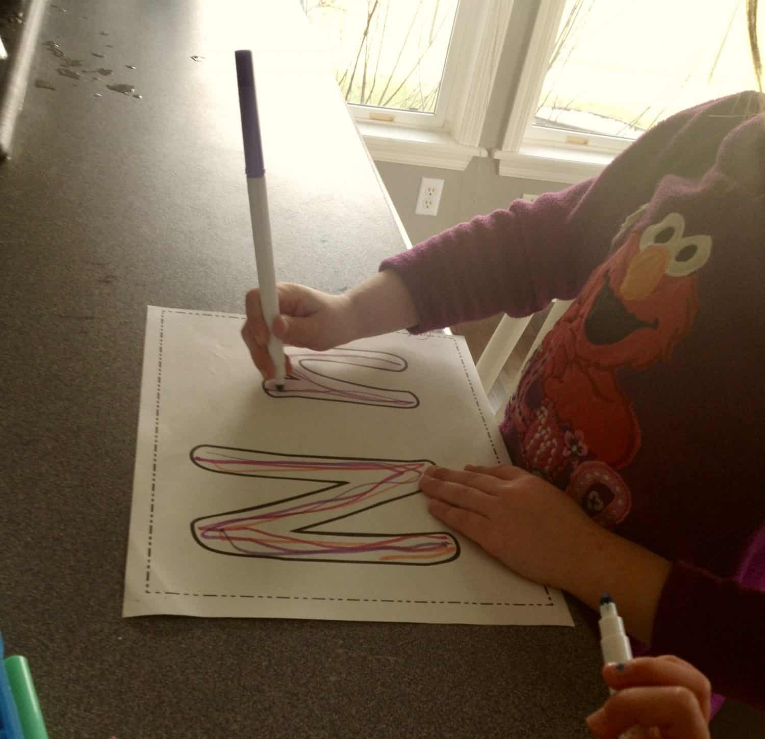 preschool girl working on writing the letter N