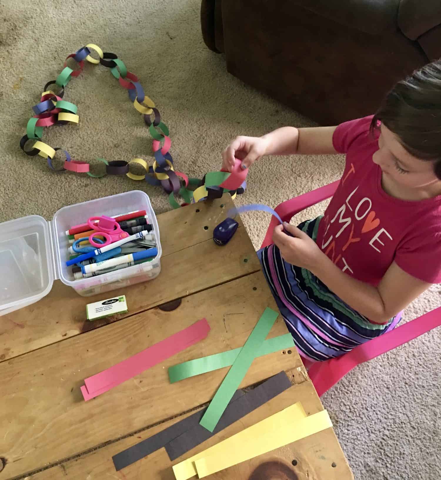 girl putting together a paper chain in the color of the Olympic rings