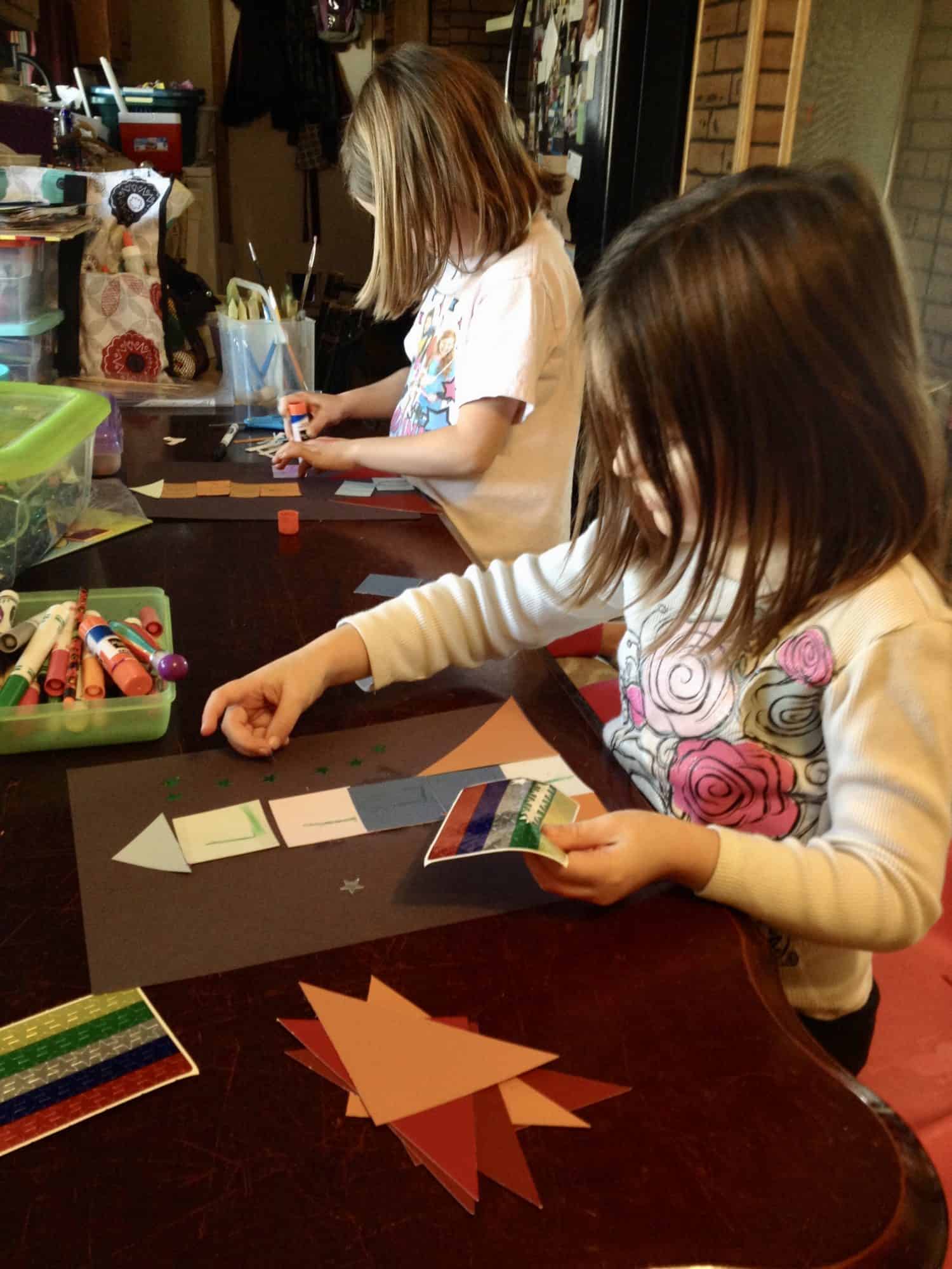 sisters working on a rocket craft at the kitchen table