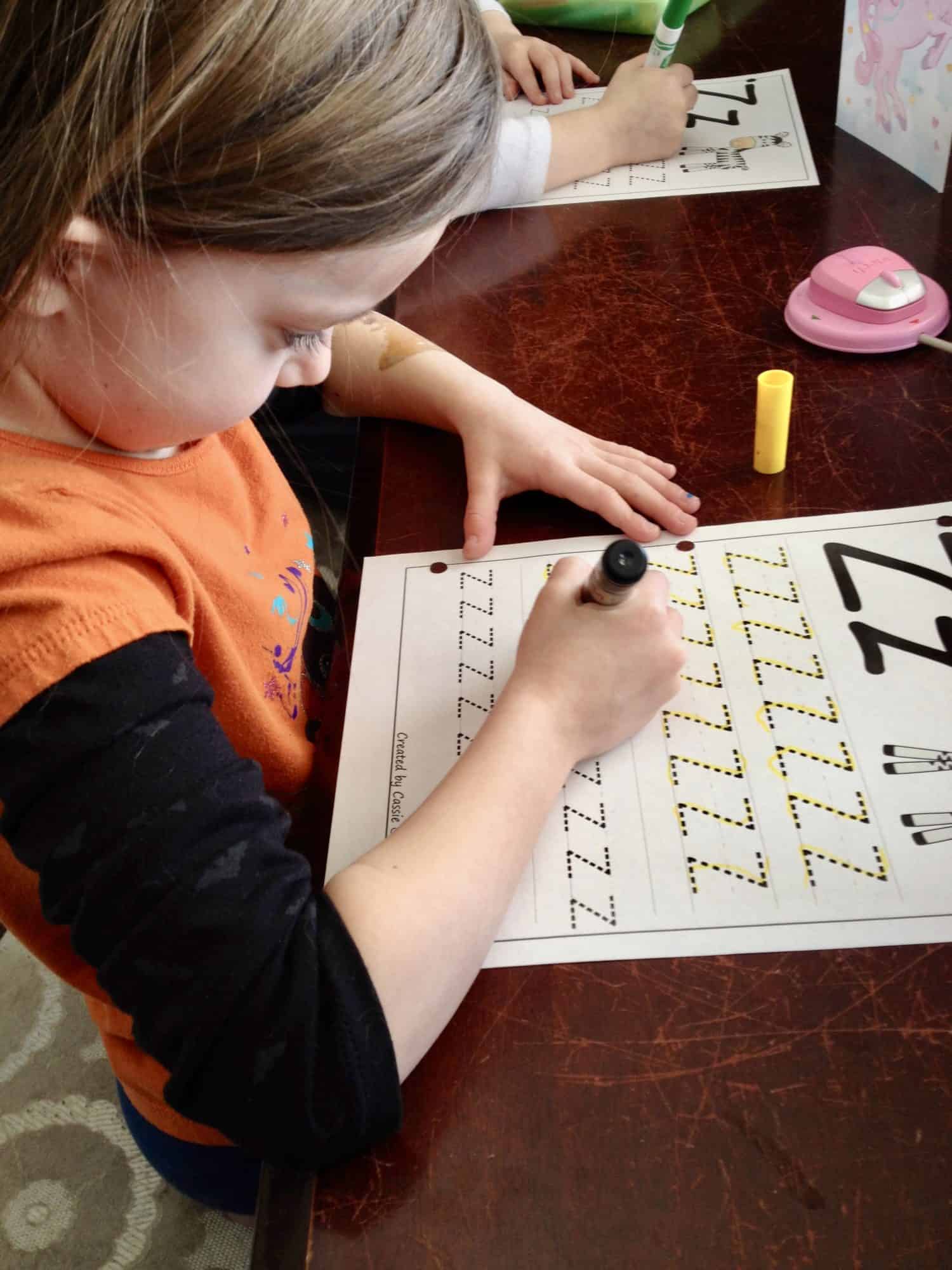 Preschool-aged girls working on tracing the letter z. 