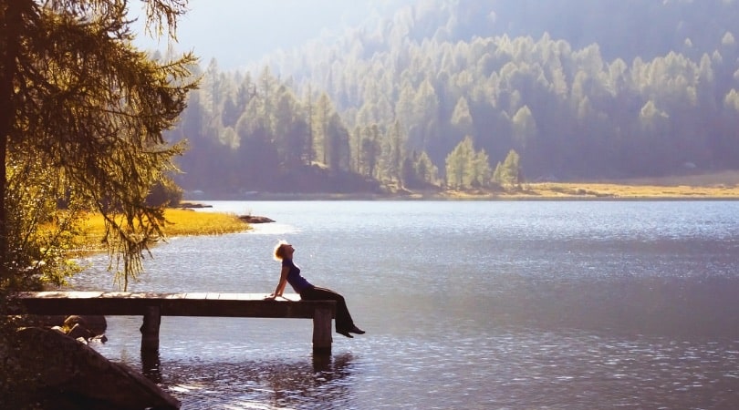 Woman relaxing on a small wooden pier at the lake. 